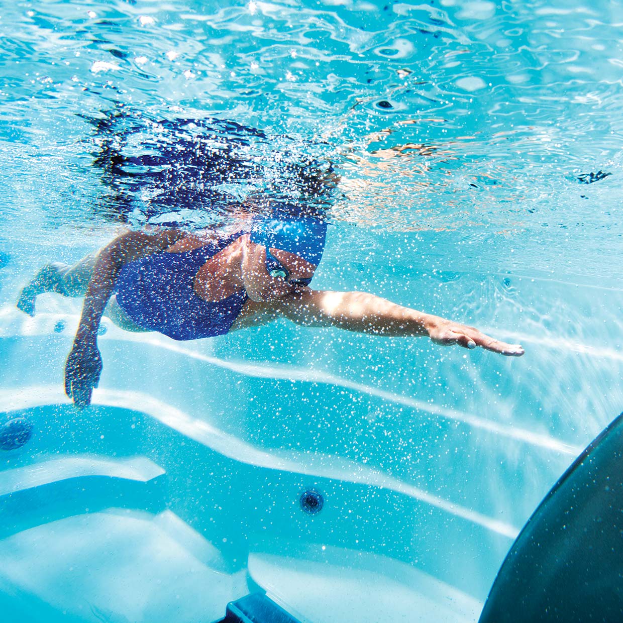 woman swimming underwater in a swim spa